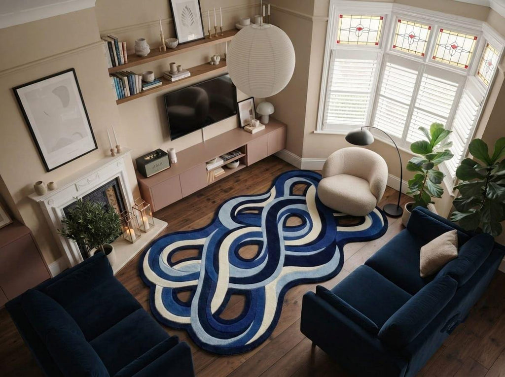 Shubham-Art-Rugs-hand-tufted-abstract-wavy-wool-rug-irregular-blue-area-carpet A modern living room featuring a prominent abstract wavy area rug in shades of blue, navy, and cream. The room is furnished with a navy blue sofa, a cream accent chair, a wooden TV stand, and a fireplace.