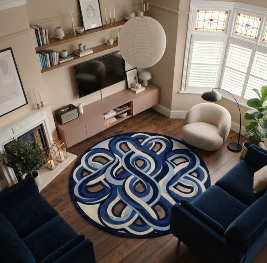 Shubham-Art-Rugs-hand-tufted-abstract-wavy-wool-rug-irregular-blue-area-carpet A round area rug with a bold blue and cream interlocking knot pattern, styled in a modern living room with a navy blue sofa, beige armchair, and wooden floors.