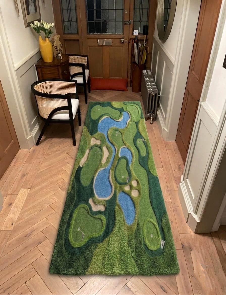 Shubham-Art-Rugs-hand-tufted-golf-course-rug-new-zealand-wool-3d-topography-sports-room-decor A long rectangular area rug with a golf course landscape design, featuring green fairways, blue water features, and sand bunkers, displayed on a light wood herringbone floor in a home hallway.