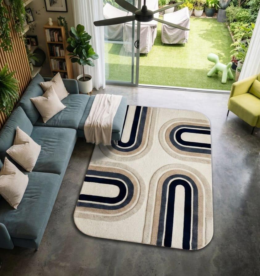 Modern-mid-century-living-room-interior-decorated-with-navy-and-beige-geometric-arch-area-carpet A modern living room scene featuring a rectangular area rug with a cream, beige, and navy blue geometric arch pattern. The rug is styled on a gray concrete floor next to a teal sectional sofa, with a glass sliding door in the background showing a backyard patio.