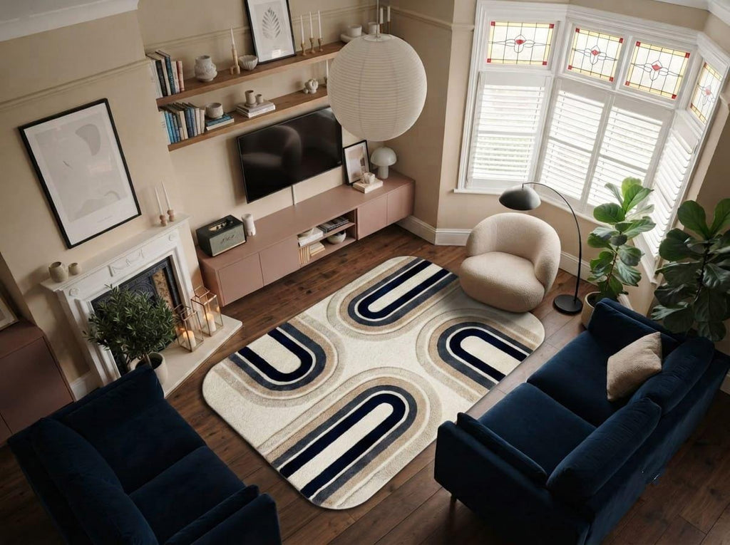 Shubham-Art-Rugs-hand-tufted-new-zealand-wool-arch-rug-navy-blue-beige-ivory-contemporary-carpet A modern living room featuring a prominent rectangular area rug with a bold geometric wave pattern in navy blue, cream, and beige. The room is styled with a navy blue sofa, a beige armchair, a pink media console, and a fireplace.
