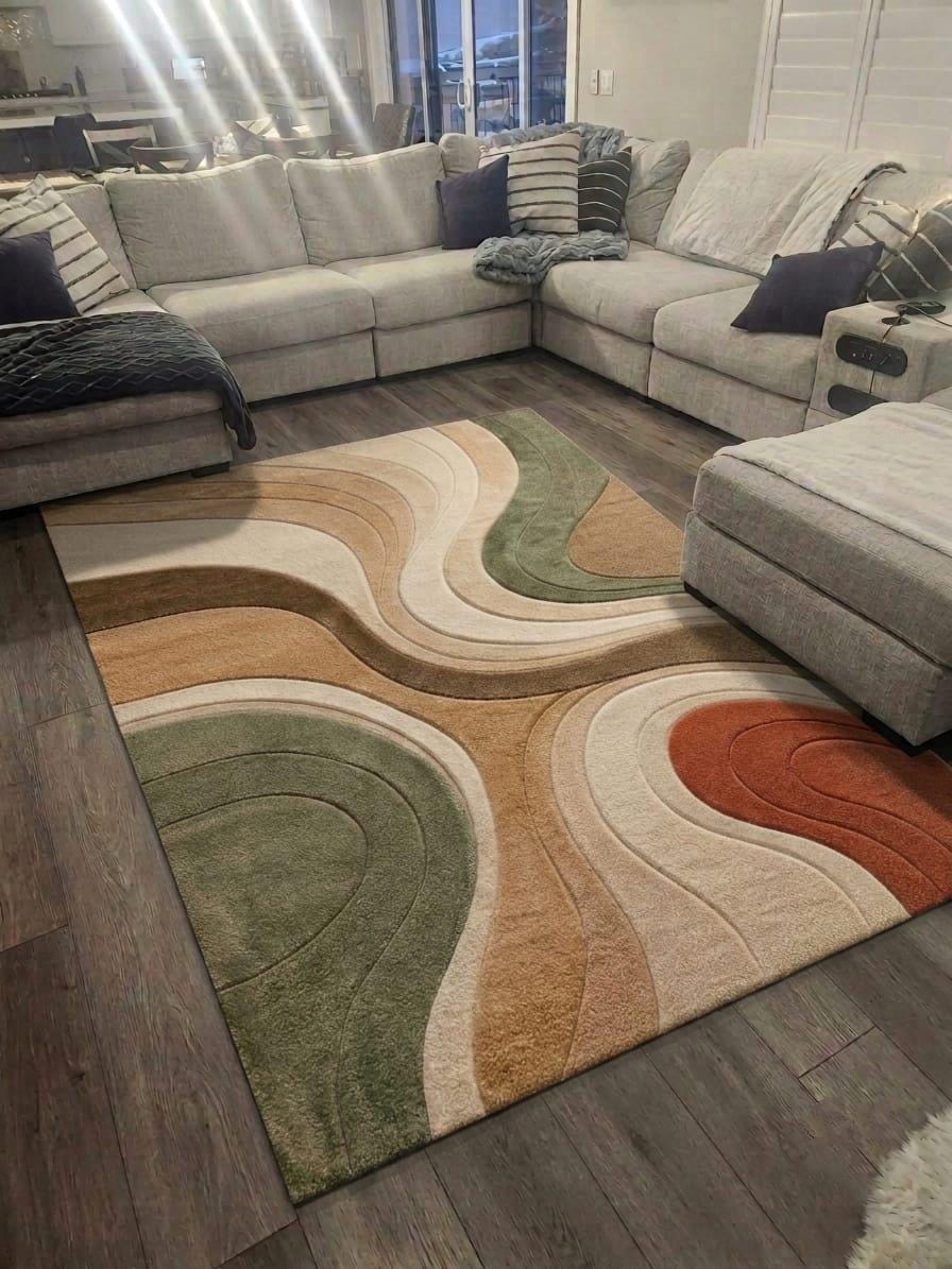 Shubham-Art-Rugs-hand-tufted-wool-area-rug-abstract-wavy-sage-green-terracotta-beige-contemporary-home-carpet A modern area rug with a wavy, organic abstract pattern in beige, brown, sage green, cream, and terracotta, styled on a dark wood floor in a living room setting.