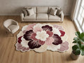 Shubham Art Rugs hand tufted New Zealand wool flower rug featuring a pink and burgundy scalloped petal layout
 A large round area rug with a bold floral pattern in shades of cream, dusty pink, mauve, and deep burgundy, styled in a modern living room setting with a beige sofa, armchair, and potted plant.