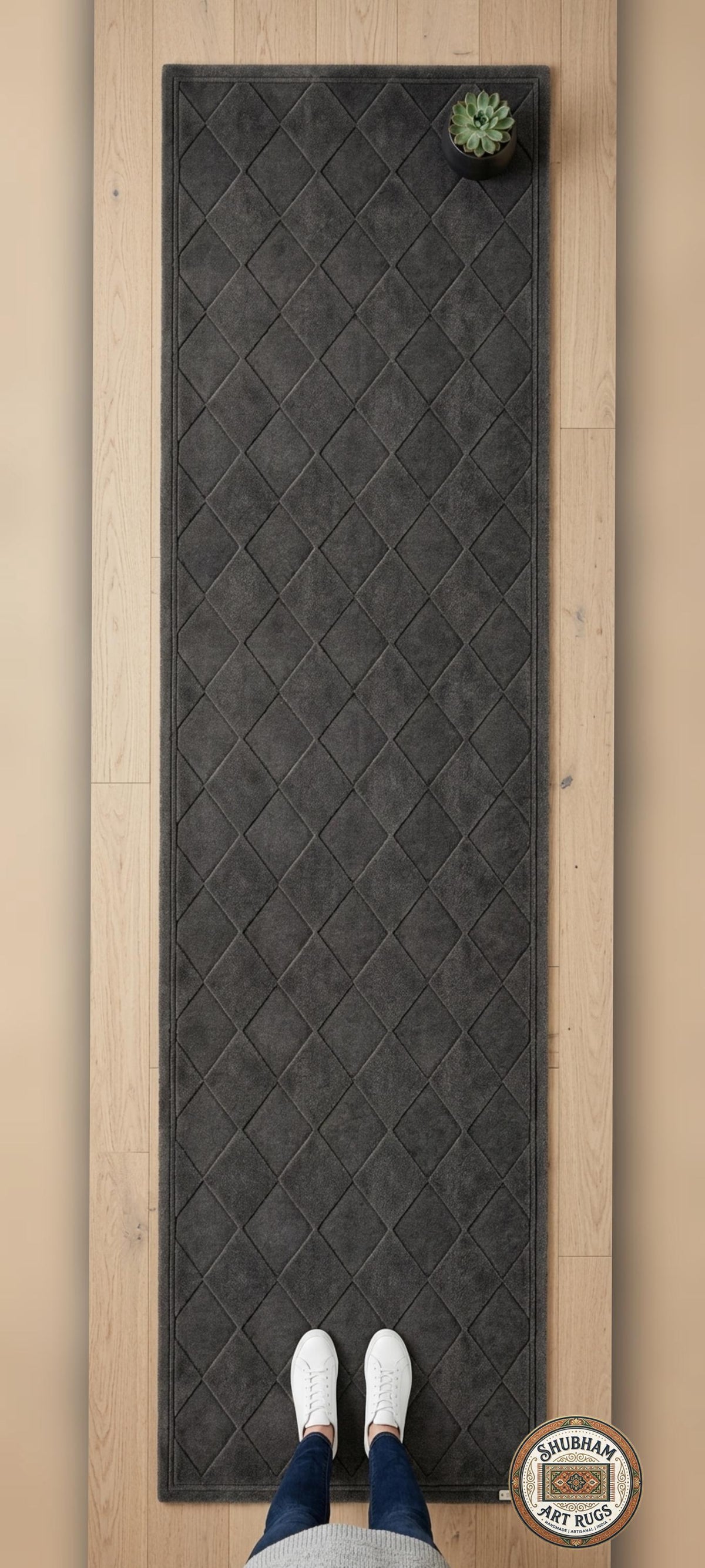 Shubham Art Rugs hand tufted wool area rug featuring a modern geometric diamond pattern in dark grey and charcoal tones
 Black textured rug on a wooden floor with a person's feet wearing white shoes and blue jeans.